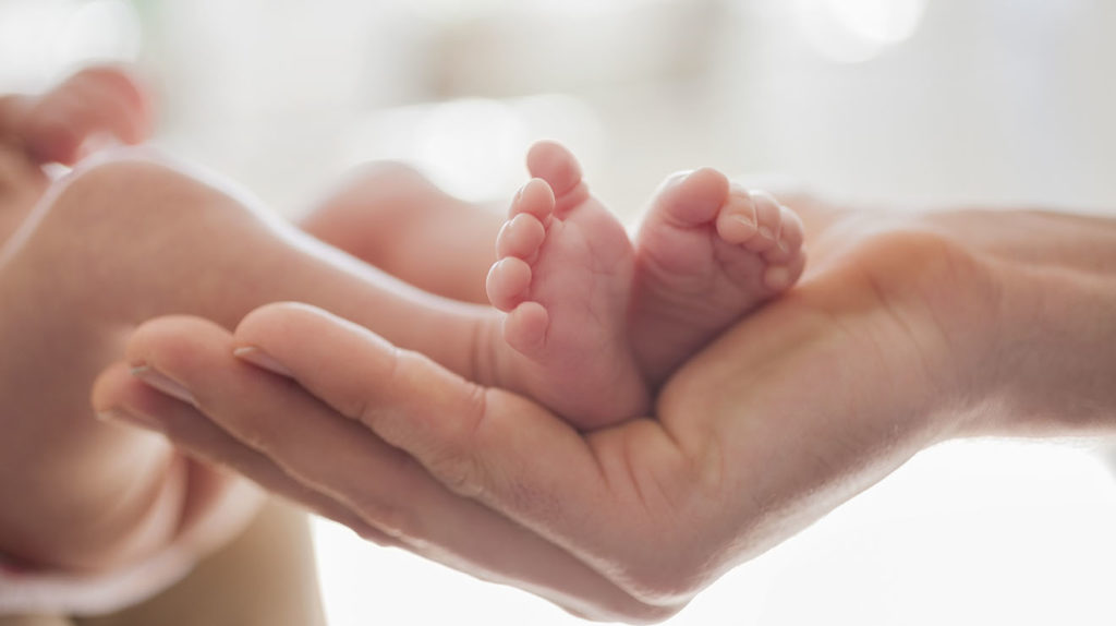 pie de bebe recén nacido en la mano de la madre