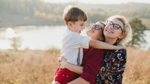 madres con su hijo se abrazan delante de un lago